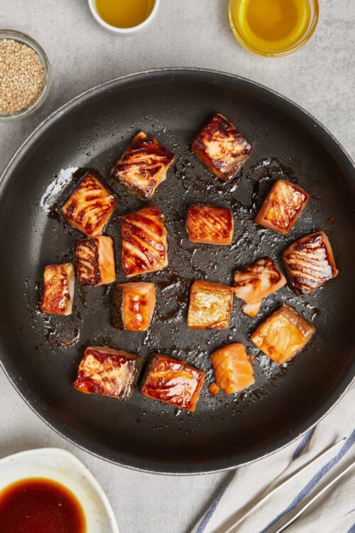 Seared pork belly cubes in a black skillet with sweet and savory glaze.