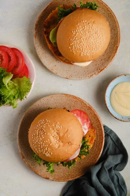 Crispy chicken sandwiches with fresh lettuce and tomatoes on ceramic plates.