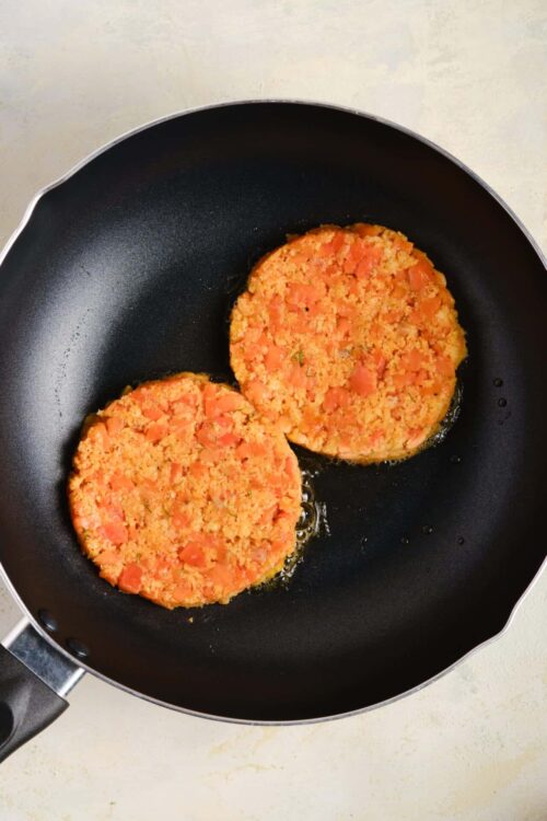 Cookies cooking in a black frying pan with oil.