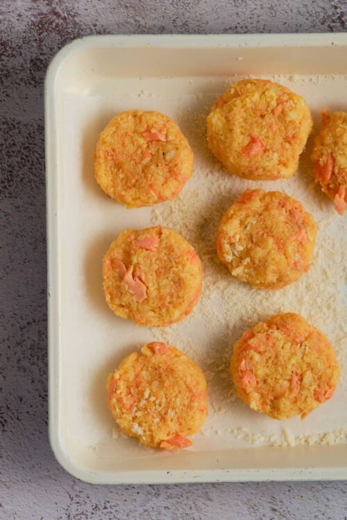 Crispy baked salmon croquettes on white baking tray.