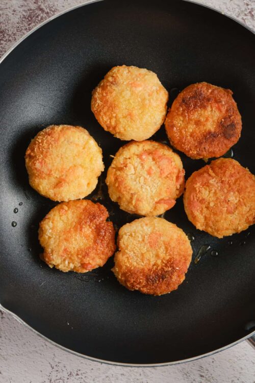 Crispy baked chicken nuggets in a black skillet with a textured background.