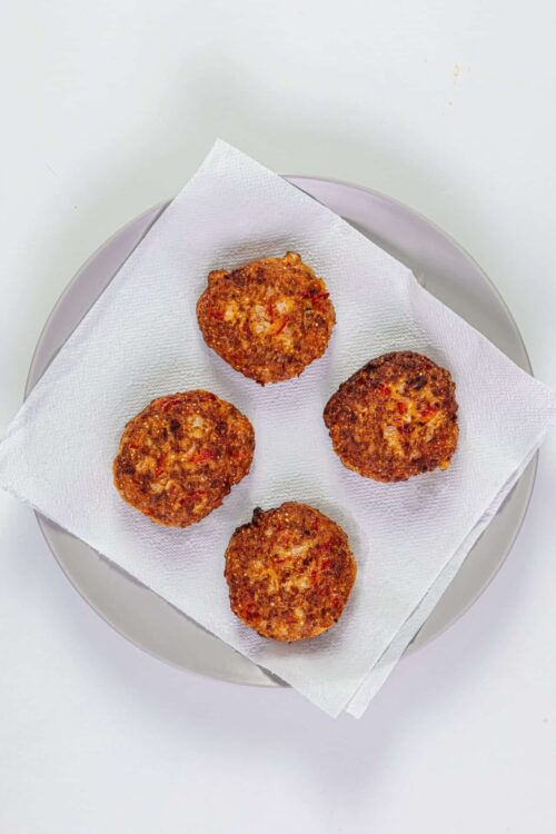 Crispy homemade meatballs with tomato sauce on white plate.