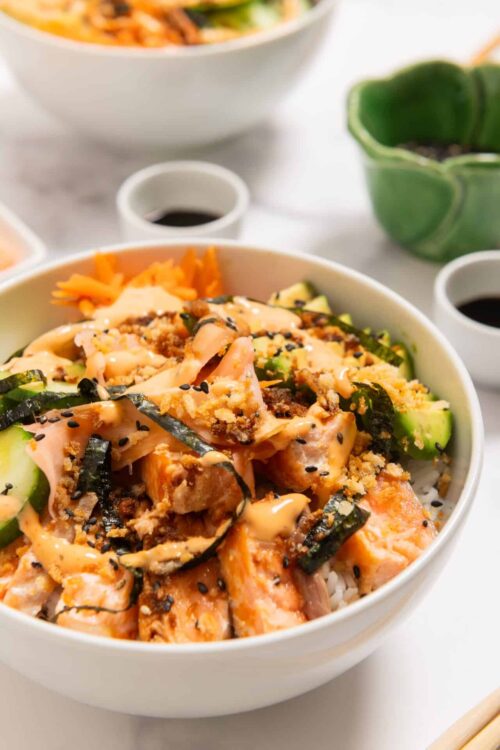 Salmon poke bowl with rice, cucumbers, and seaweed.