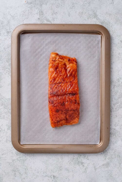 Baked salmon fillet with crispy, glazed surface on parchment paper.