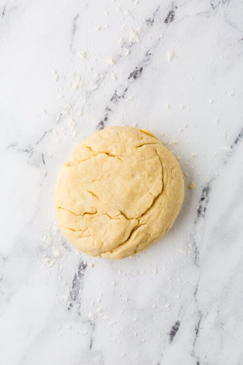 Buttery classic pie dough ball on marble surface, ready for baking.