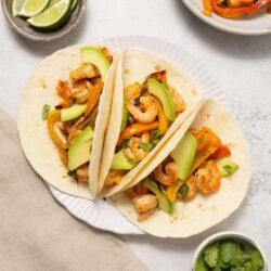 Fresh shrimp and vegetable tacos in soft flour tortillas with avocado slices and cilantro.