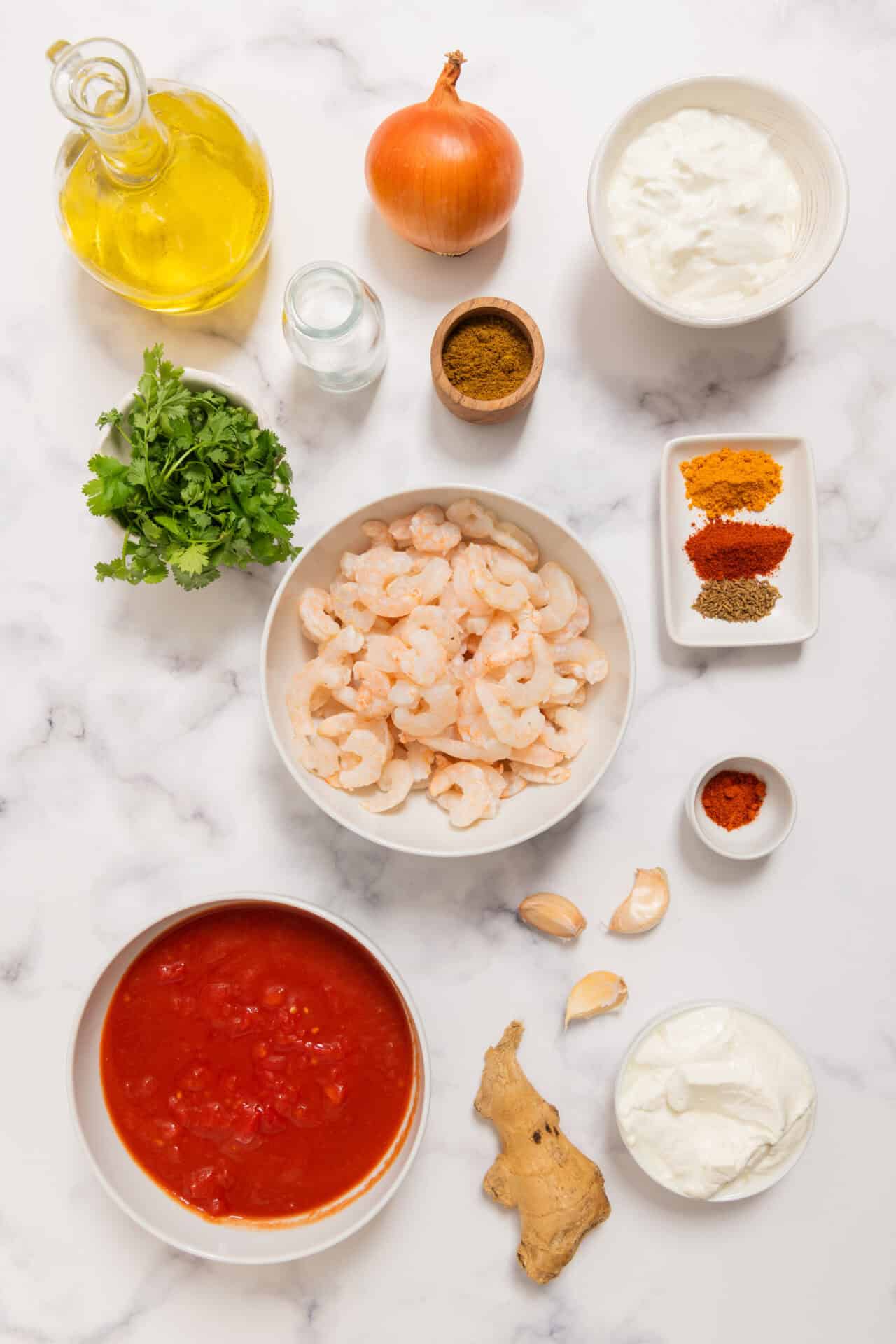 Fresh shrimp, onions, garlic, spices, and yogurt for flavorful shrimp curry preparation.