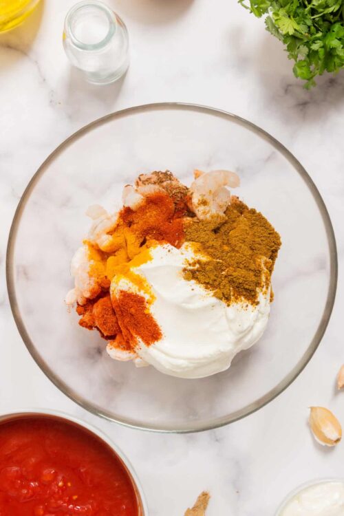 Mixed spices and ingredients in a glass bowl for flavorful chicken marinade or recipe.