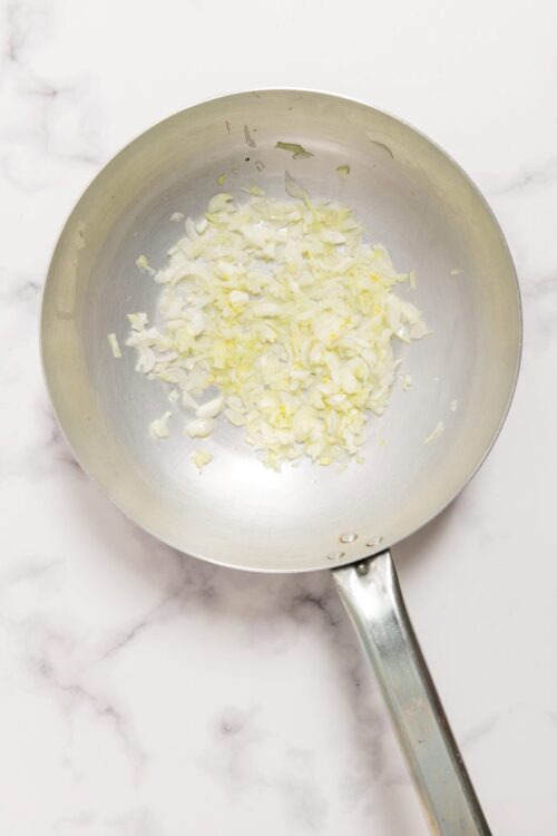 Sautéed chopped onions in a stainless steel skillet for cooking or recipe preparation.