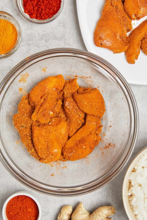 Breaded chicken breasts for baking with spices and ingredients for homemade fried chicken.