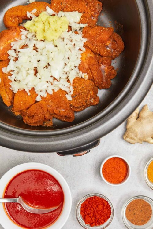 Slow cooker chicken marinated with spices and topped with chopped onions, garlic, and ginger for flavorful chicken curry.