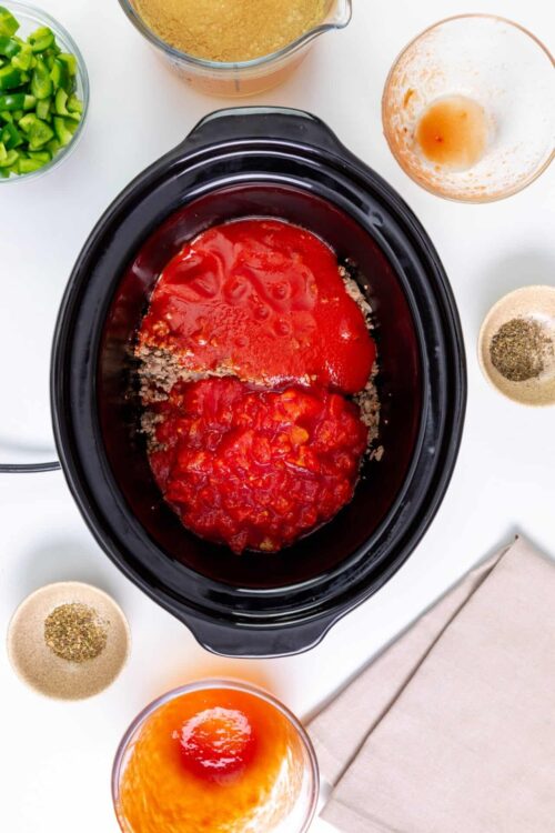 Slow cooker with tomato sauce and ground meat ingredients for a delicious homemade recipe.