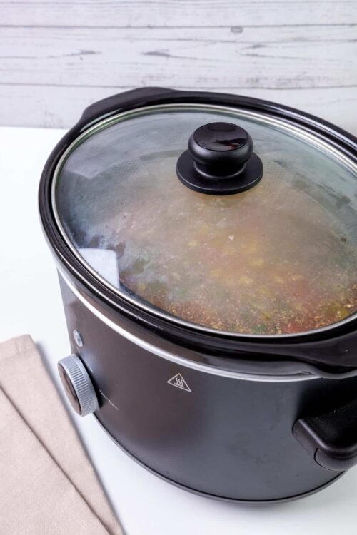 Slow cooker with soup or stew cooking inside.
