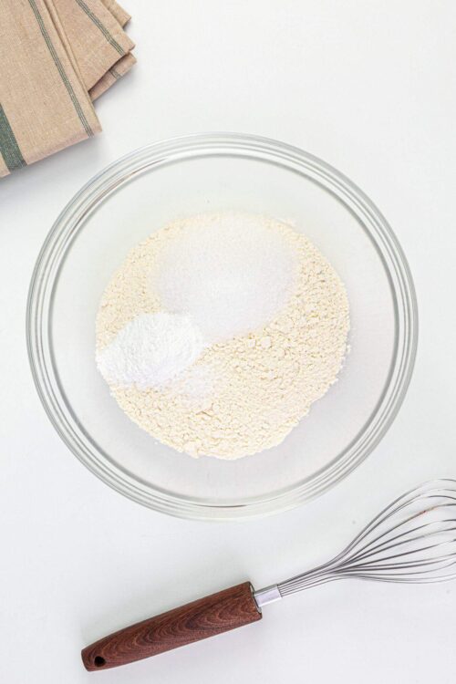 Flour, baking powder, and salt in a glass mixing bowl for baking bread or pastries.