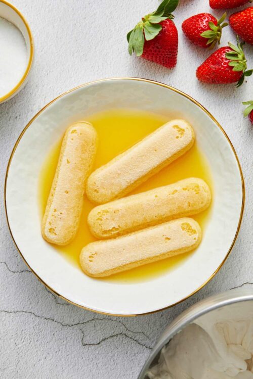 Fluffy ladyfingers soaking in lemon syrup for tiramisu dessert.