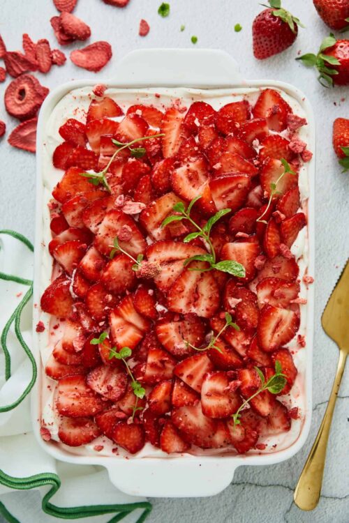 Fresh strawberry dessert with sliced strawberries and mint garnish in a white baking dish.