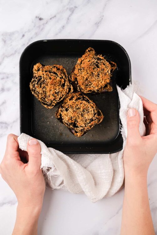 Crispy baked stuffed portobello mushrooms on black baking dish.