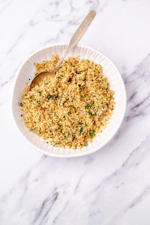 Crunchy seasoned breadcrumb topping on a white dish of baked casserole or stuffing.