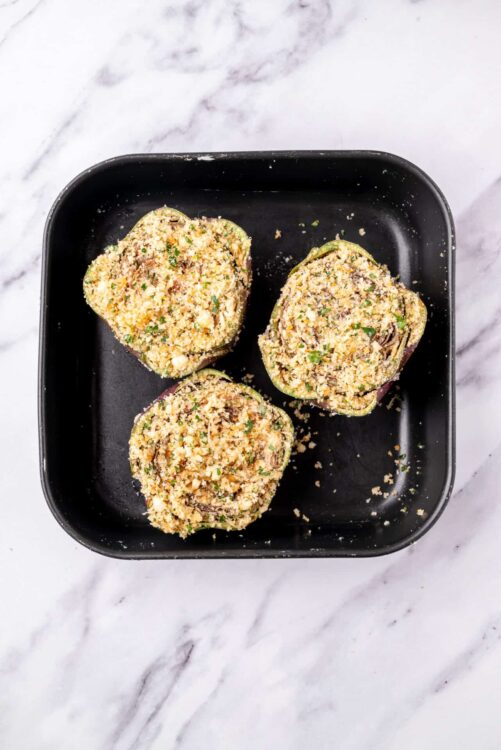 Crunchy stuffed mushroom caps prepared for baking on black dish.