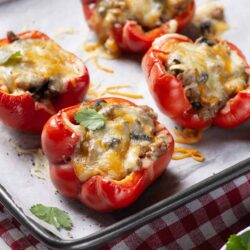 Stuffed red bell peppers with cheese, ground meat, and vegetables, baked to golden perfection. Perfect healthy dinner or appetizer.