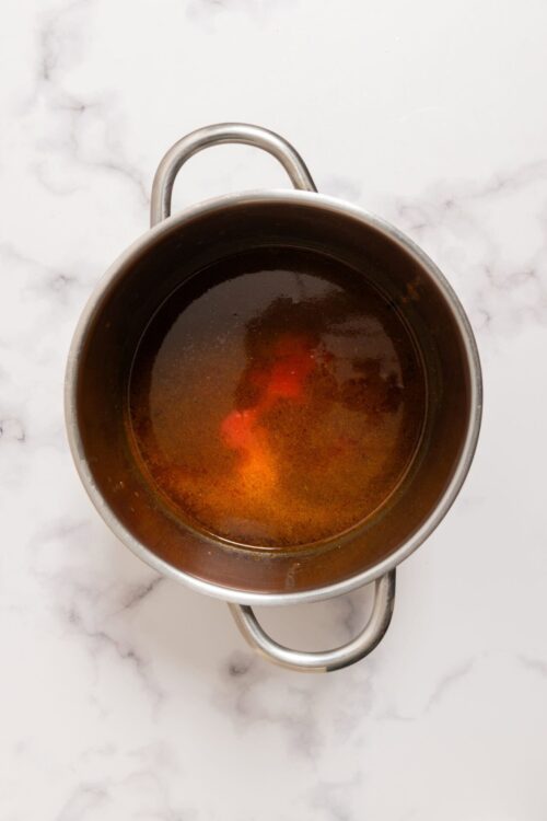 Brewing hot tea in a metal teapot on marble countertop.