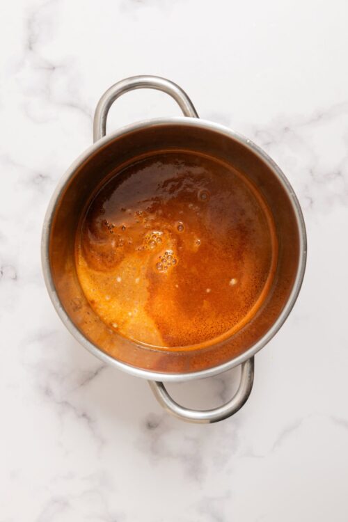 Brewing hot caramel sauce in stainless steel pot, ready for dessert or baking.