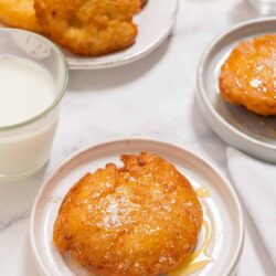 Golden fried chicken breast on white plate with syrup drizzle.