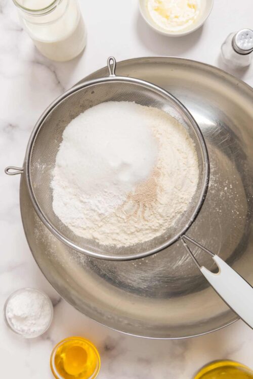Flour being sifted in a stainless steel flour sifter for baking.