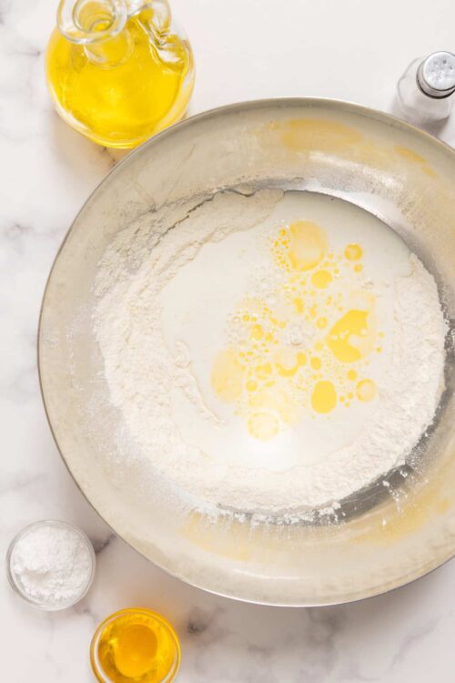 Flour, milk, and eggs in a mixing bowl for baking bread or pastry.