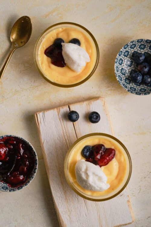 Creamy lemon custard with blueberry topping and whipped cream on glass dessert cups.