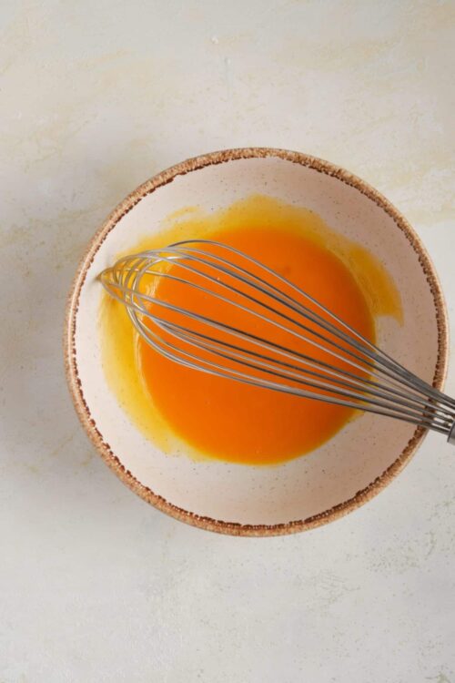 Whisked eggs in a rustic bowl for baking recipes.