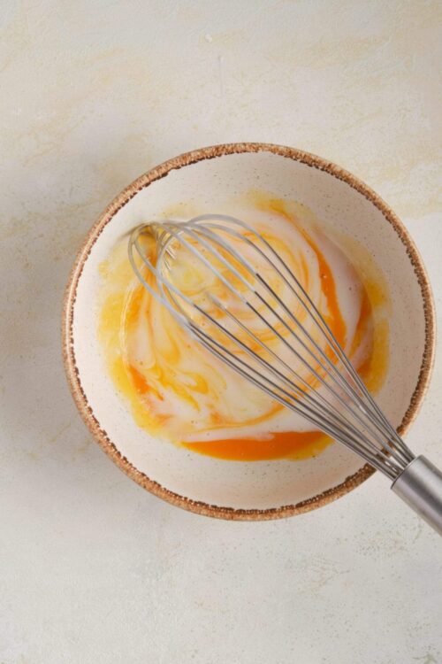 Whisked eggs in a ceramic bowl for baking or cooking recipes.