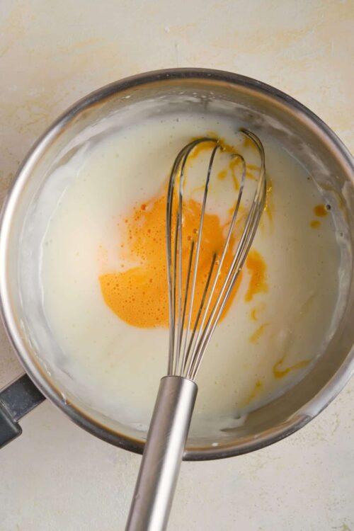 Creamy mixture with eggs in a mixing bowl for baking recipes.
