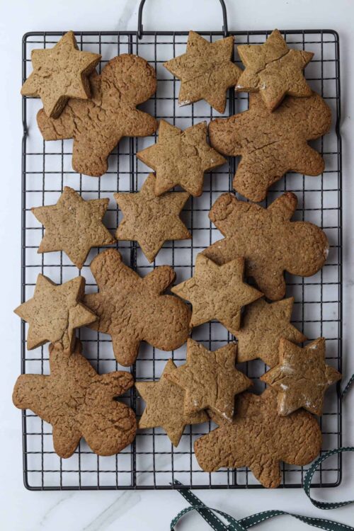 Soft ginger cookies on a cooling rack, decorated with holiday-themed cookie cutters.