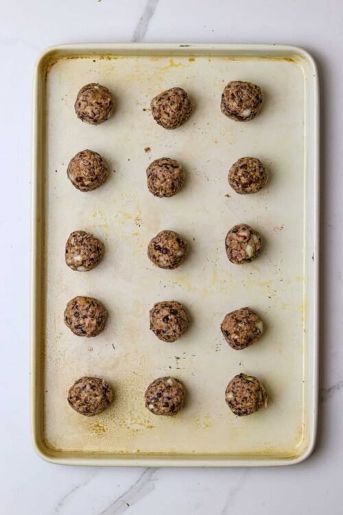 Chocolate chip cookie dough balls on a baking sheet before baking.