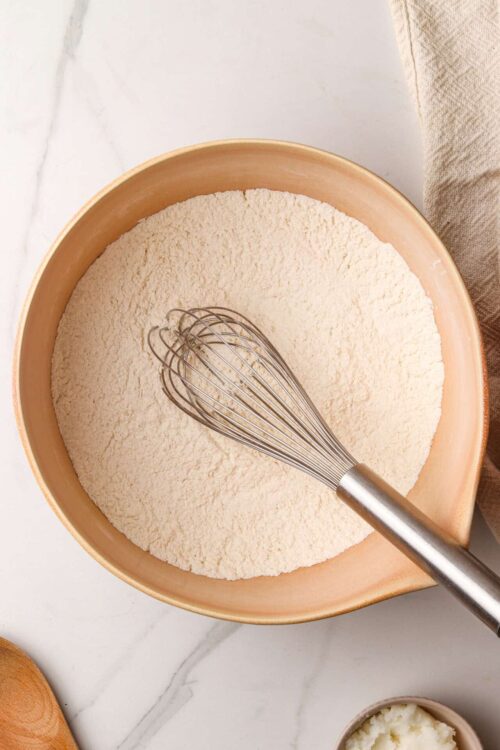 Flour in a mixing bowl with a whisk for baking recipes.