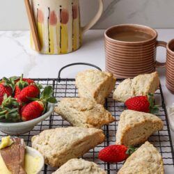 Flaky scones on a cooling rack with fresh strawberries and butter. Perfect for breakfast or tea, easy homemade scones recipe from Baked Bree.