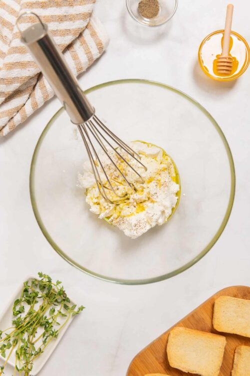 Cream cheese mixture with honey and spices in a glass bowl for cheesy garlic bread recipe.