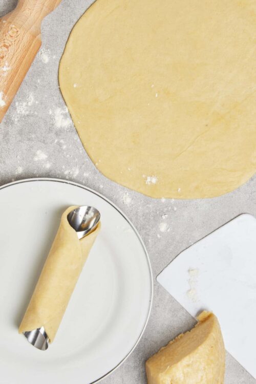 Golden pastry dough being rolled out on a floured surface for baking.
