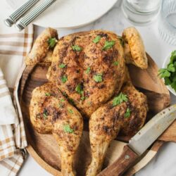 Juicy roasted whole chicken with crispy skin garnished with fresh parsley.