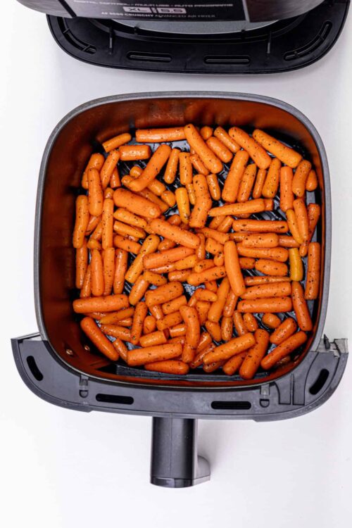 Roasted baby carrots in an air fryer basket.