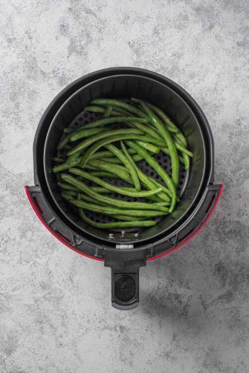 Fresh green beans in air fryer basket for healthy recipes.