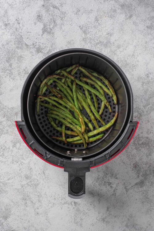 Cooked green beans in air fryer basket.