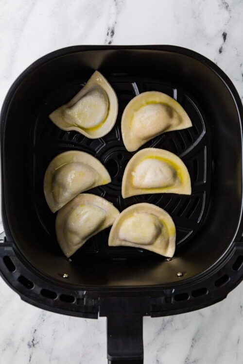 Air fryer dumplings with crescent-shaped dough pockets ready to cook.