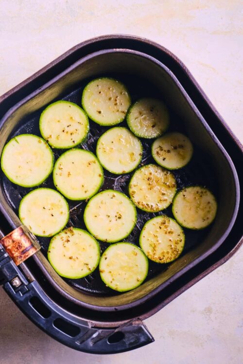 Sliced zucchini in air fryer, fresh vegetable Italian side dish, healthy zucchini recipe, baked zucchini in air fryer, delicious zucchini kitchen inspiration.