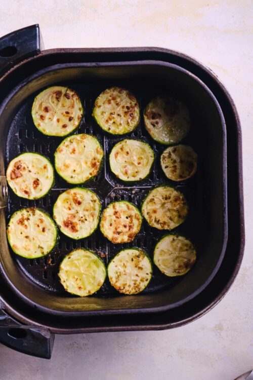 Baked zucchini slices in an air fryer, golden and tender, perfect healthy snack or side dish.