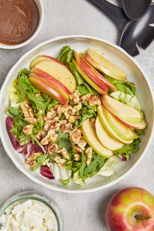 Sliced apple and walnut salad with mixed greens, cheese, and apple slices.