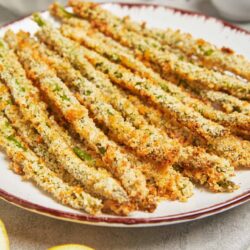 Crispy baked asparagus fries with golden breadcrumb coating on a white plate.