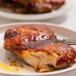 Succulent baked chicken thigh with barbecue glaze on white plate, delicious comfort food, easy dinner recipe.