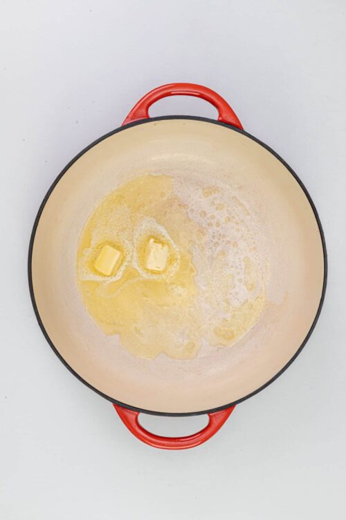 Butter melting in a red Dutch oven for baking or cooking recipes.